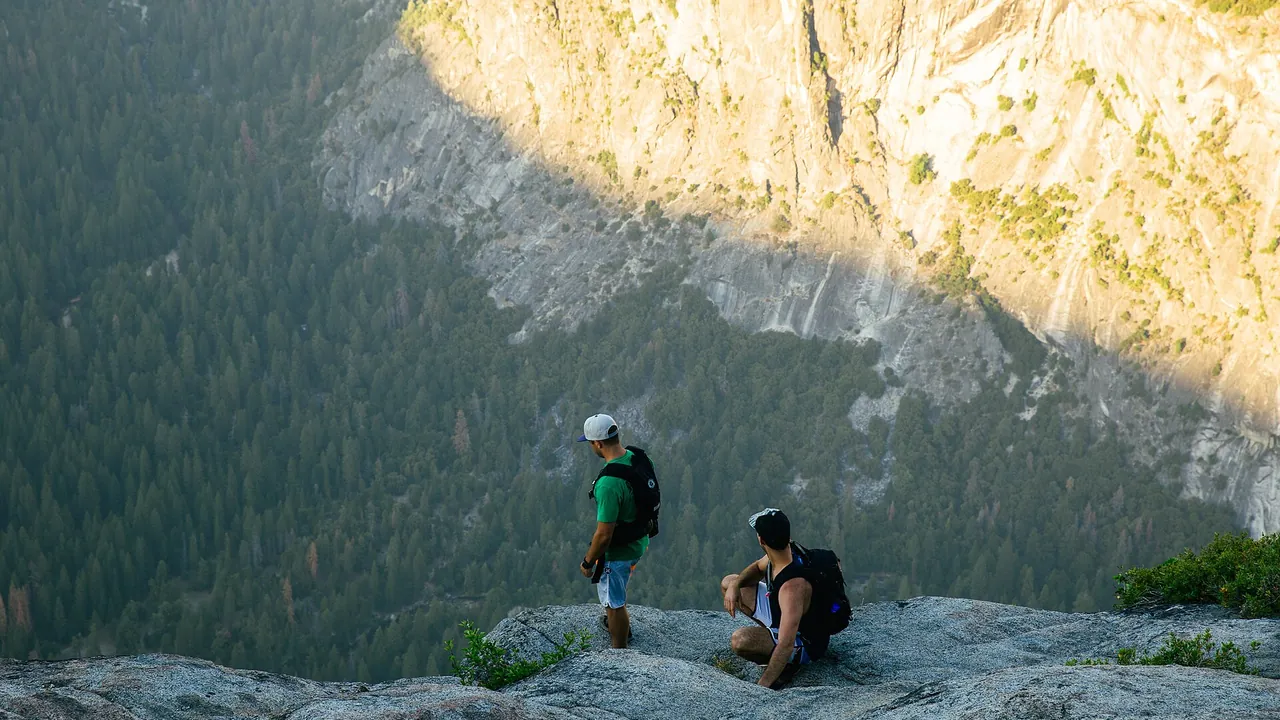 Two hikers cliff top — warm lifestyle scene
